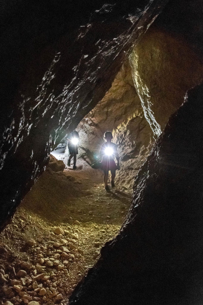 Photo of kids hiking in cave with a flashlight